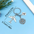 Travel keychain with metal airplane, compass and passport charms on light blue background - Plane Passport Compass (ER678)