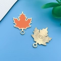 Golden maple leaf pendant with orange enamel and textured radiating pattern on the back - Orange Enamel Maple Leaf