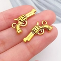 Pendentif revolver doré en alliage pour bijoux DIY présenté sur le bout du doigt - Pistolet Or Antique (19252)