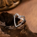 Vista de detalle del anillo de corazón martillado plateado sobre fondo de madera - Estilo Corazón Hueco Martillado (4022-2 Plateado)