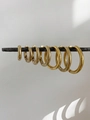 Vista macro de siete tamaños de pendientes de aro de acero dorado en una barra metal - 14mm (1 Par) / Dorado