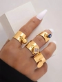 Detalle de cuatro anillos de acero dorado con dijes de ojo turco y circón en la mano - Juego de Ojo Turco/Cuadrado/Disco Redondo / Set de 4 piezas / Dorado