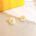 Macro detail of S925 daisy stud earrings with white petals and yellow centers - White