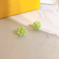 Detailed view of daisy stud earrings with green petals and yellow centers on marble surface - Green