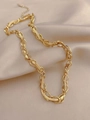 Detalle de collar de cadena dorada de varias capas sobre fondo de seda color champán - Tejido Dorado