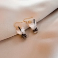 Detail of creative milk tea resin earrings with pearl accents on golden satin background - Original Flavor