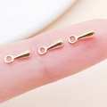 Three rose gold teardrop charm connectors on a fingertip for DIY jewelry making - 7x2.5mm / KC Gold