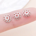 Calottes de perles fleurs argentées pour bijoux DIY présentées sur le bout d'un doigt - 7mm / Couleur Or Blanc