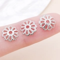 Calottes de perles fleurs argentées pour bijoux posées sur le bout des doigts - 9mm / Couleur Or Blanc