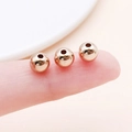 Three rose gold spherical beads with mirror polish on a fingertip for size perspective - Round (14079) / 1 Piece/Pack (6mm) / KC Gold