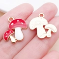DIY mushroom charms in gold alloy and red enamel shown in hand for size reference - Red Enamel Double Mushroom Small (17001)