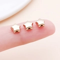 Drei winzige goldene Stern-Zwischenperlen auf einer Fingerspitze für DIY-Schmuck - Sternen-Abstandsperle (14142)