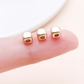3 goldene CCB Würfel-Zwischenperlen für DIY-Schmuck auf einer Fingerspitze präsentiert - Quadratische Abstandsperle (14143)