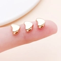 Drei kleine herzförmige Gold-Zwischenperlen auf einer Fingerspitze für DIY-Schmuck - Herzförmige Abstandsperle (14145)