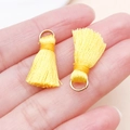 Mini pendentif gland jaune avec anneau doré tenu en main pour comparer la taille - Jaune d'Or