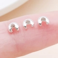 Three small silver metal U-shaped jewelry end crimp covers placed on a fingertip - 3x4x2.4mm / Silver - Small