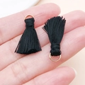 Mini pompon noir avec anneau doré tenu entre les doigts pour bijoux faits à la main - Noir