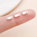 Three silver-plated metal crimp ends for jewelry making shown on fingertips for scale - Small / Bright Silver Polished Style