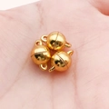 Trois fermoirs magnétiques ronds dorés pour bijoux DIY présentés dans la paume d'une main - Grande Sphère Dorée Lisse