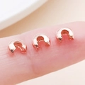 Three rose gold crimp bead covers held between fingers to show micro scale size - Rose Gold-Medium