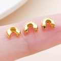 Three gold-plated copper C-shaped crimp bead covers shown on a finger for scale - Gold-Medium