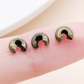 Three bronze metal crescent crimp beads for jewelry making shown on fingertips - Bronze - Medium