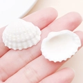 Two small white scallop shell pendants for DIY jewelry making held in a palm for size - Drilled Creamy White Scallop Shell