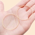 Minimalist large golden brass hoop earrings shown on hand for scale size reference - 40mm / Gold