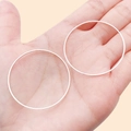 Minimalist large silver round hoop earrings held in hand for size visualization - 40mm / Bright Silver