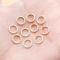 Rose gold round copper jump rings for jewelry making shown in hand for scale - 8mm / KC Gold