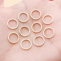 Set of ten glossy gold geometric round metal rings for DIY jewelry making displayed on palm - 10mm / KC Gold