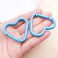 Moschettone a cuore in alluminio celeste tenuto in mano per scala dimensionale - Blu