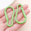 Coppia di moschettoni in alluminio verde brillante a forma di pera tenuti in mano - Verde