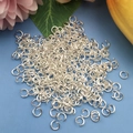 Macro di anellini aperti in argento per gioielli fai-da-te su sfondo floreale blu - 8x1.2mm / Argento Lucido