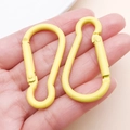 Pair of yellow aluminum gourd-shaped carabiners held in hand for size comparison - Yellow