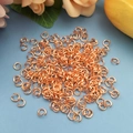Nahaufnahme von roségoldenen Biegeringen für DIY-Schmuck auf hellblauem Hintergrund - Roségold