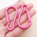Pair of pink matte pear-shaped aluminum carabiners held in hand for scale - Rose Red