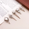 Detailed view of five vintage silver bird skull alloy charms on a retro book background - Mixed Styles (SN22)