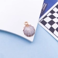 Golden shell charm with purple enamel and circular ring on a light blue background - White Shell / 13x18mm