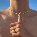 Detalle del collar con colgante de ojo de mal de oro bajo el cielo azul con cadena de serpiente - Cadena de Tubo Cuadrado Dorado