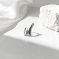 Detalle de anillo geométrico de titanio pulido sobre piedra blanca con tela de seda - Forma Escultórica Minimalista (40452-2)