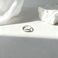 Vista macro detallada de un anillo espiral plateado sobre seda blanca y piedra - Diseño de espiral - Plateado