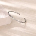 Minimalist silver open cuff bracelet with bubble-shaped edges on a stone display - Silver-like Texture / Silver