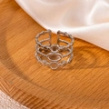 Dettaglio dell'anello geometrico in argento su elegante sfondo di seta e legno - Anello Cavo Geometrico a Tre Strati (#0483)