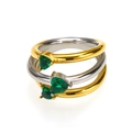 Dettaglio macro di anelli impilati con zirconi verdi a cuore e finitura in metallo lucido - Bicolore Oro Argento Zircone Verde