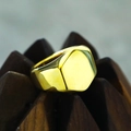 Polished gold hexagonal signet ring in titanium steel on a dark geometric wood base - Gold
