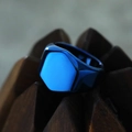 Macro shot of blue electroplated hexagonal signet ring on dark geometric wood display - US 7 / Blue