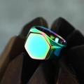 Macro shot of minimalist iridescent hexagonal titanium steel ring on a wooden stand - US 7 / Rainbow