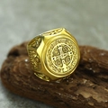 Macro shot of gold Saint Benedict cross ring with engraved relief on dark wood base - US 7 / Gold