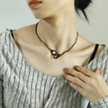 Close-up of a trendy black handcuff pendant necklace on a model's neck for a punk look - Black